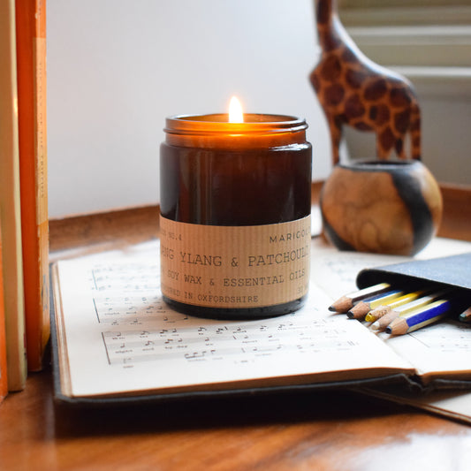 Marigold charms Ylang Ylang & Patchouli Eco Soy wax candle  on music book with pencils