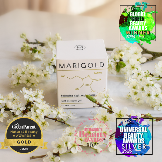 MARIGOLD balancing night cream box is centered among white blossoms on a soft light background, with several award badges around the product including Green Parent, Natural Beauty Awards Gold 2026, Natural Beauty Awards 2026, and Universal Beauty Awards Silver 2026.