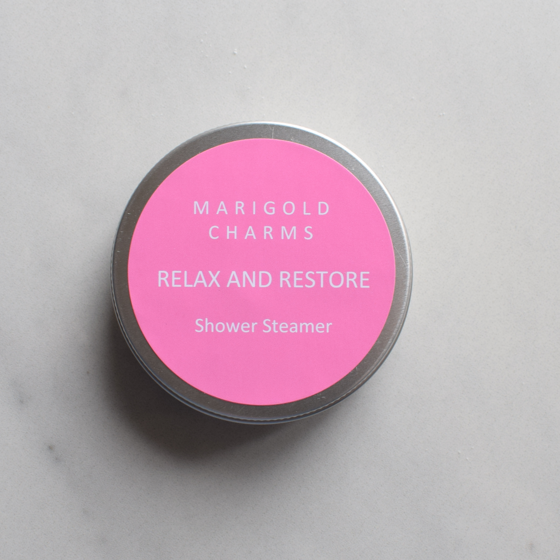 Marigold Charms rose maroc shower steamer with pink label on a marble surface