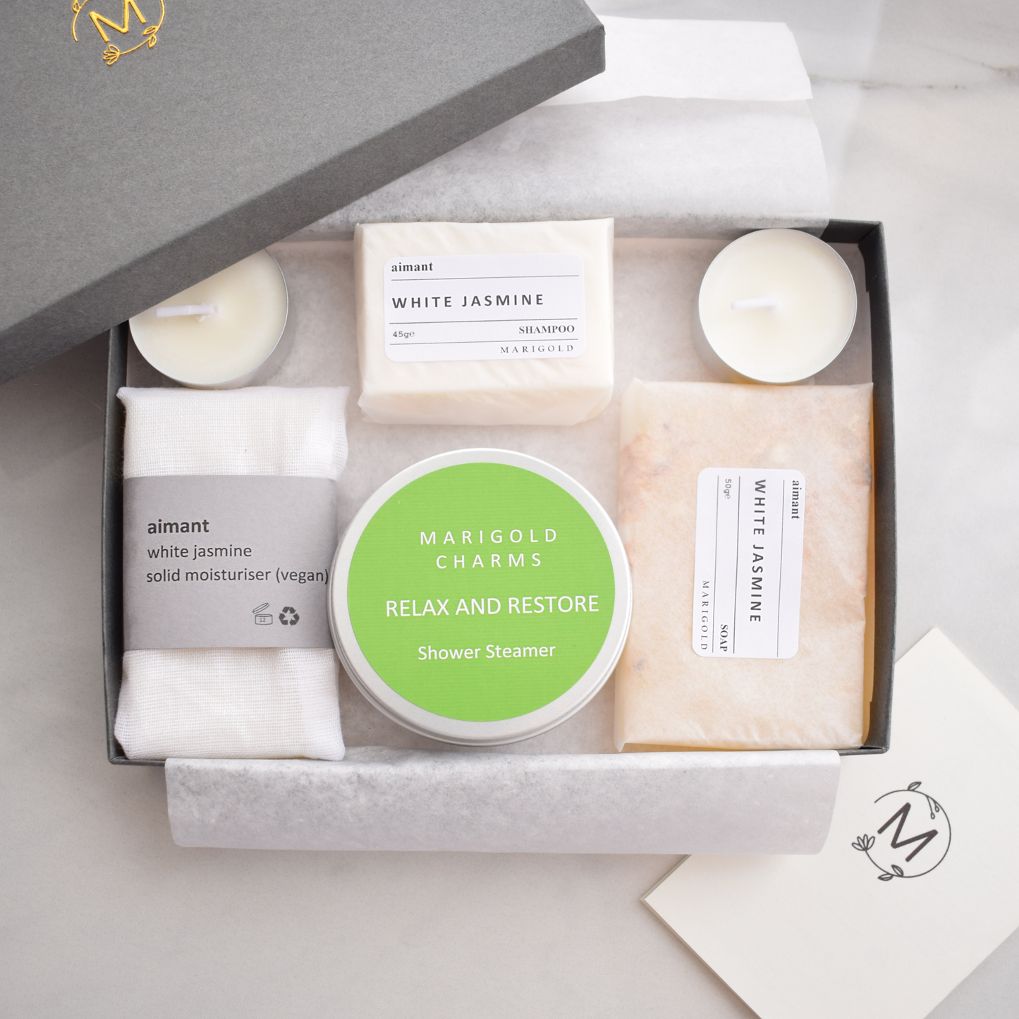 Grooming set with candles, soap, and a shower steamer in a box on a light background