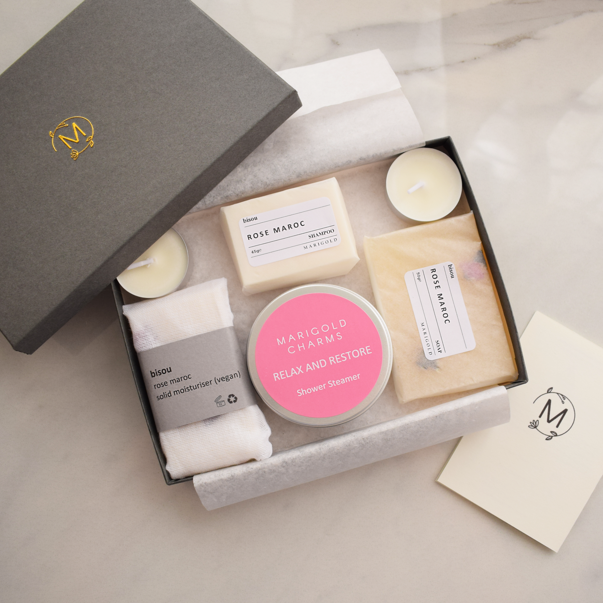 Grooming kit with soaps, candles, and a jar labeled 'Marigold Charms' in a branded box.