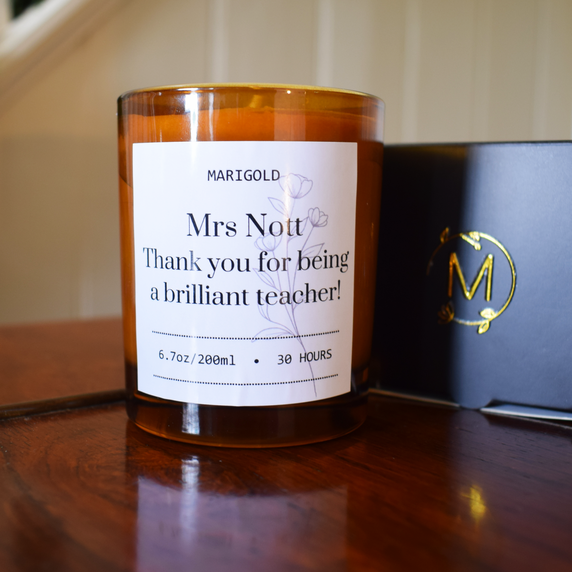 Candle with a label thanking a teacher on a wooden surface